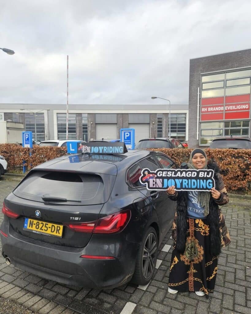 Geslaagde cursist van Rijschool EnjoyRiding toont trots haar rijbewijs bij de lesauto Geslaagde cursist van Rijschool EnjoyRiding toont trots haar rijbewijs bij de lesauto
