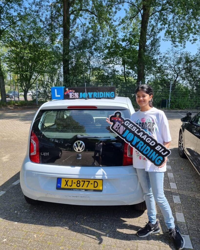 Geslaagde leerling van Rijschool EnjoyRiding poseert trots met certificaat bij lesauto Geslaagde leerling van Rijschool EnjoyRiding poseert trots met certificaat bij lesauto