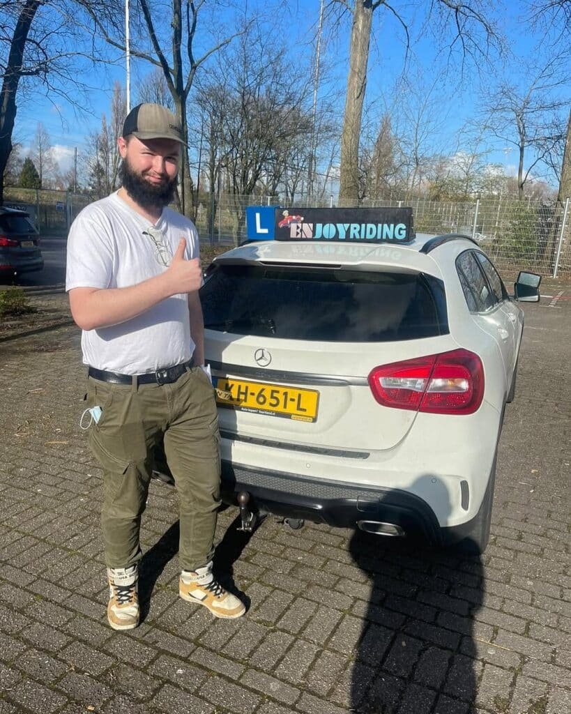 Tevreden cursist toont duim omhoog na geslaagd rijexamen bij rijschool EnjoyRiding lesauto Tevreden cursist toont duim omhoog na geslaagd rijexamen bij rijschool EnjoyRiding lesauto