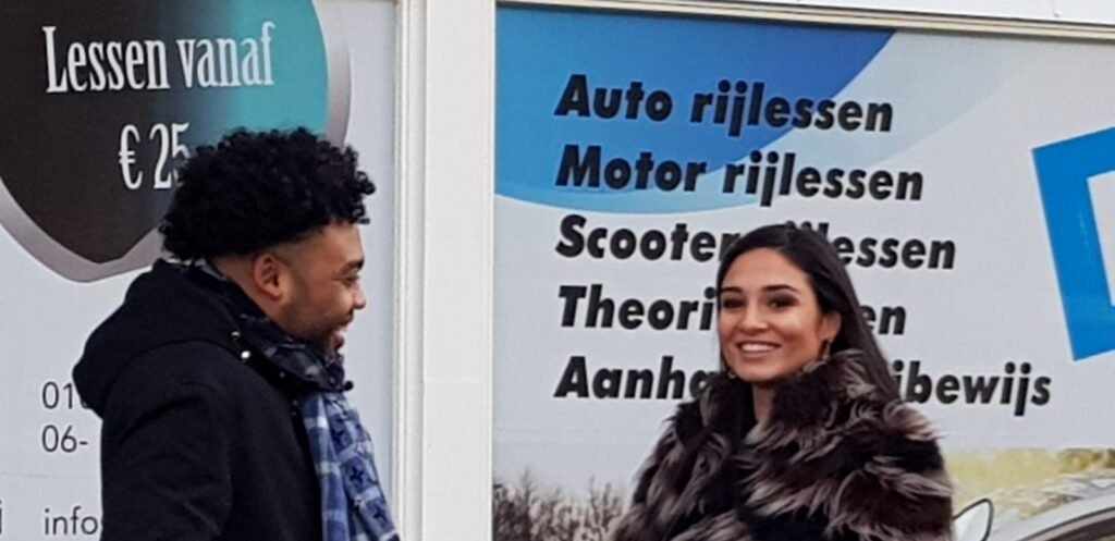 Twee mensen in gesprek bij informatiebord rijschool met rijlessen en theorie-examens